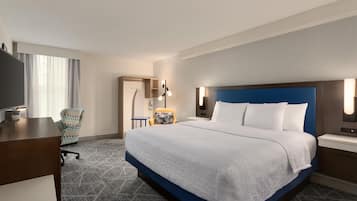 Une chambre d’hôtel avec un grand lit, un bureau, une chaise et un téléviseur.