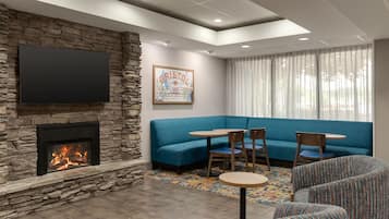 A living room with a stone fireplace, a flat-screen TV mounted above it, a blue sofa, and a patterned rug.