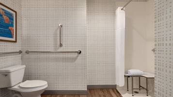 A bathroom with a toilet, grab bars, a shower curtain, and a towel rack.