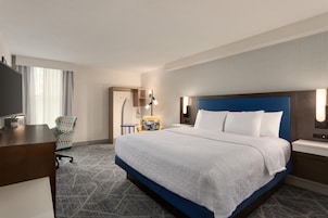 Una habitación de hotel con una cama grande, un escritorio, una silla y un televisor.