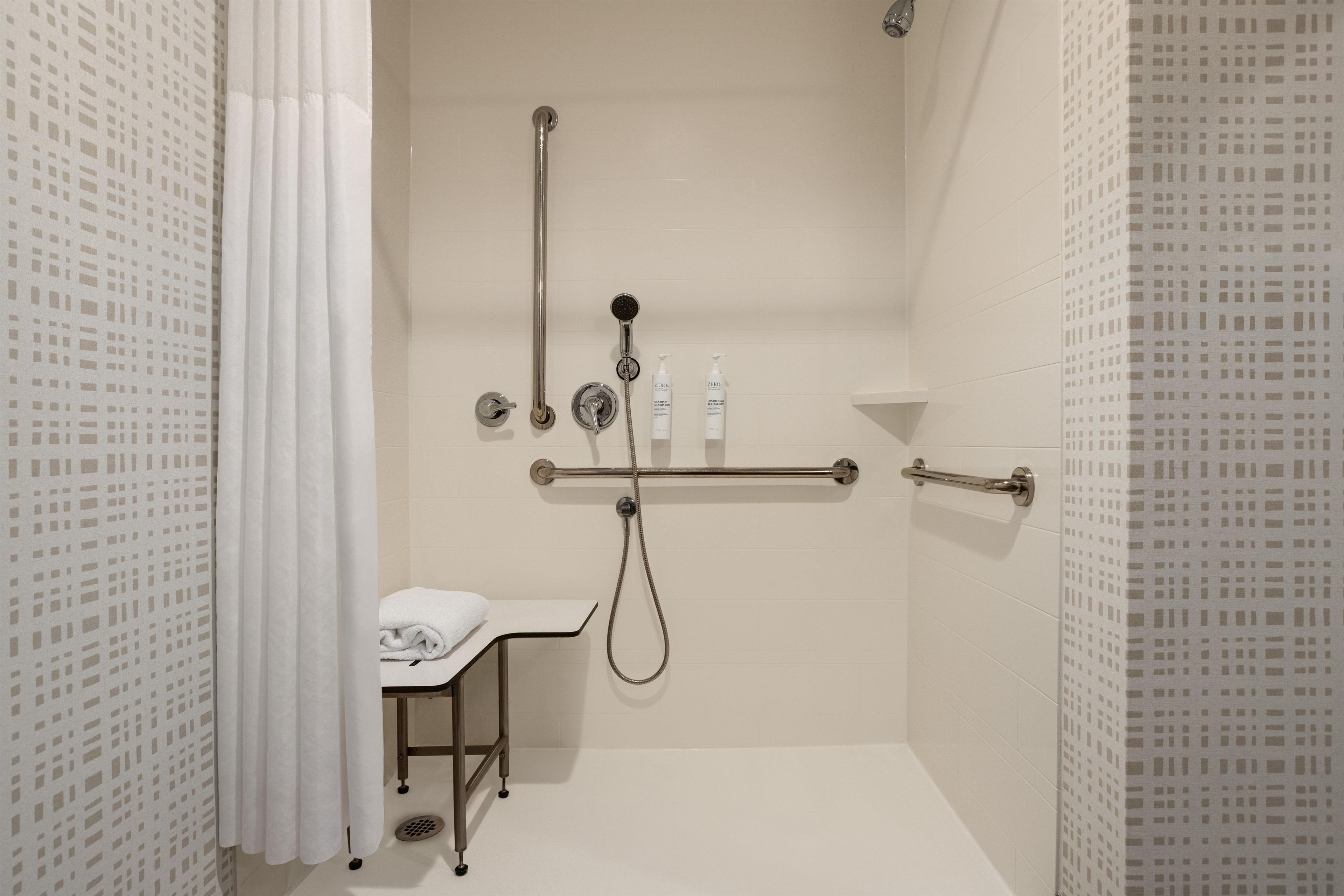 Un baño moderno con ducha a nivel, inodoro y lavabo.