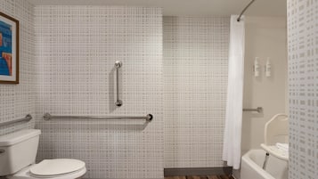 Ein Badezimmer mit Toilette, einer Dusche mit Haltegriff und einer Badewanne.