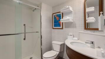 Een moderne badkamer met een douchecabine van glas, een toilet, een wastafel met spiegel en een handdoekrek.