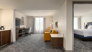 A hotel room with a bed, a desk with a chair, a sofa, and a television.