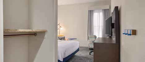 Une chambre d’hôtel équipée d’un lit, d’un bureau, d’une chaise, d’une télévision et d’un mini-bar.