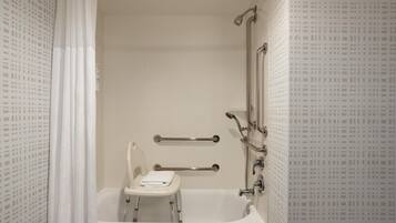 A bathroom with a bathtub, a shower, and a toilet. There are grab bars installed for safety.