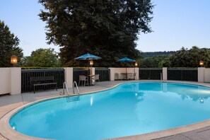A swimming pool with a surrounding deck, two umbrellas, and a table with chairs. - Hampton Inn Bristol (Bristol)
