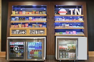 Una máquina expendedora con aperitivos y bebidas, y un refrigerador con bebidas y productos lácteos.