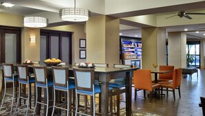 A modern dining area with a long table, multiple chairs, and a decorative centerpiece. - Hampton Inn Collierville (Collierville)