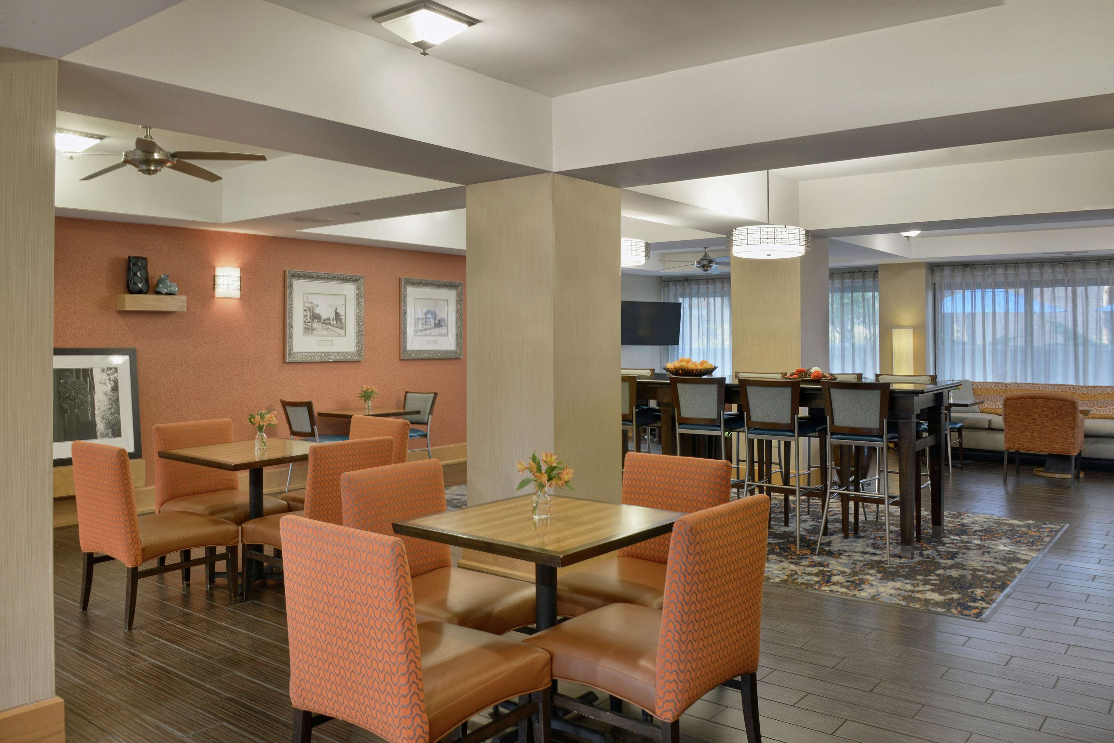 A hotel room with a dining area, a sofa, a TV, and a ceiling fan.
