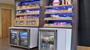 A snack display with various packaged goods and a refrigerated beverage dispenser. - Hampton Inn Collierville (Collierville)