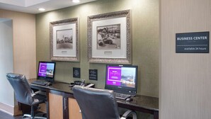 A business center with two computer stations, framed pictures on the wall, and a sign indicating 24-hour availability. - Hampton Inn Collierville (Collierville)