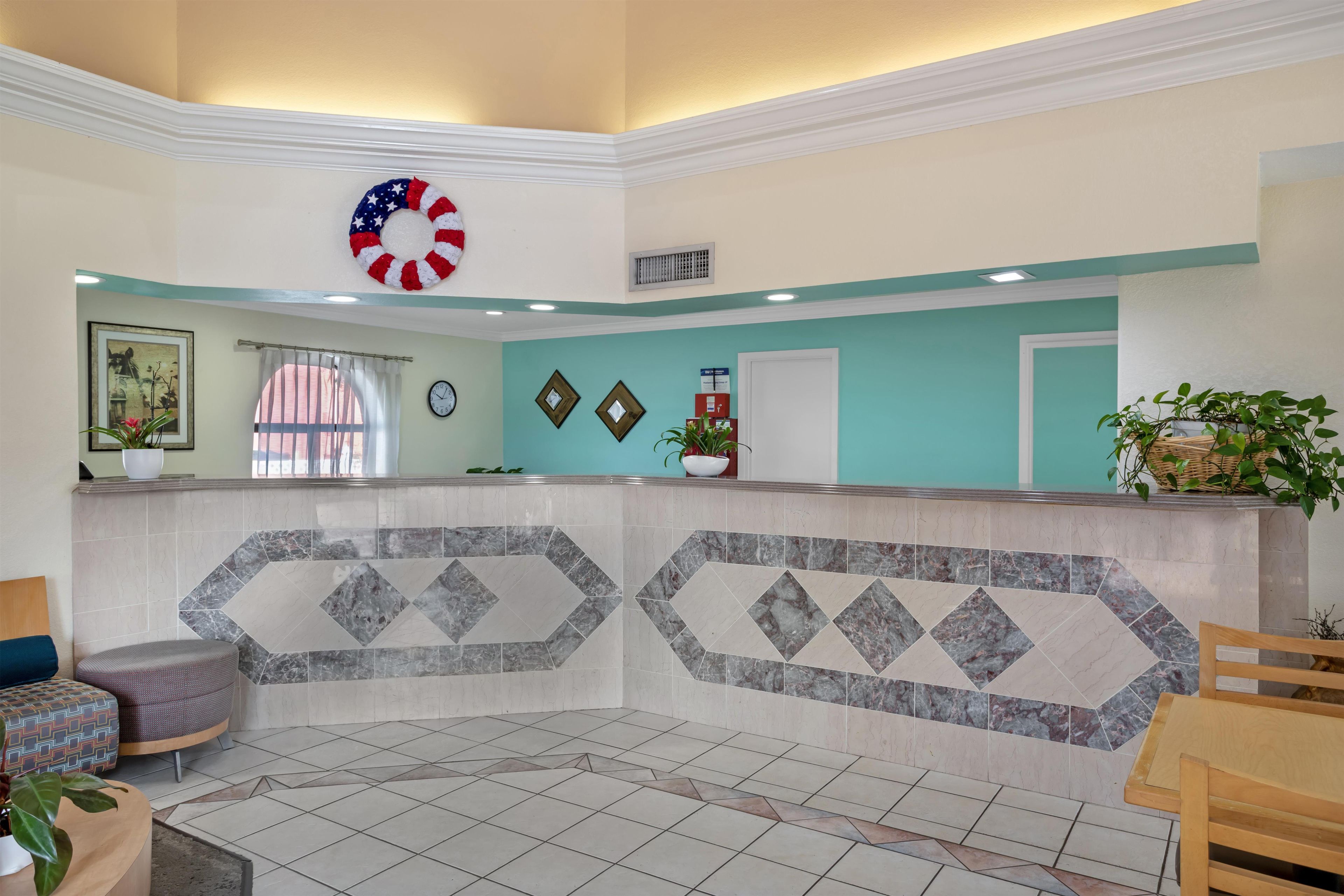 Un área de recepción con un mostrador de diseño marmolado, un reloj y una decoración de la bandera estadounidense.