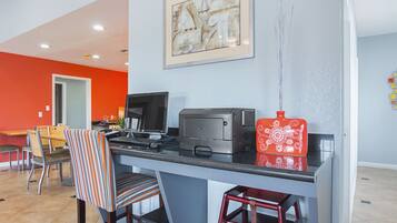 A modern kitchen with a dining area, featuring a countertop with a coffee machine, a printer, and a red decorative item.