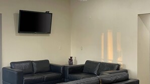 A living room with a sectional sofa, a flat-screen TV mounted on the wall, and a small decorative vase on a side table. - Econo Lodge Inn & Suites Sweetwater I-20 (Sweetwater)