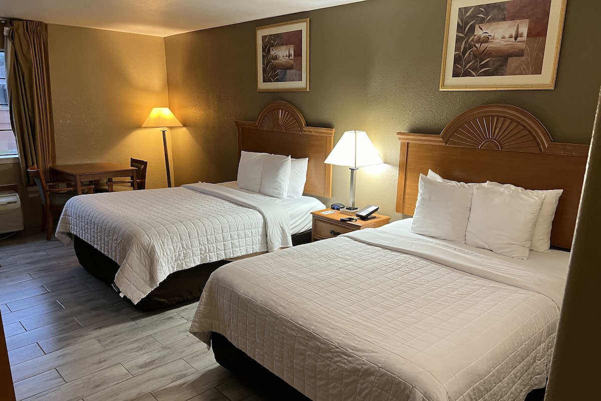 A hotel room with two beds, a desk, and a chair.