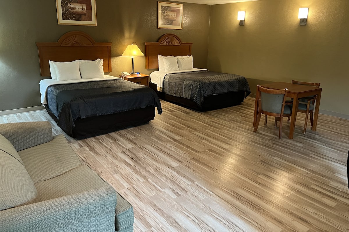 A hotel room with two beds, a desk, and a chair.