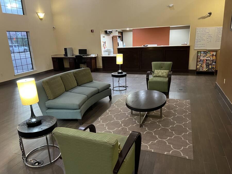 Eine Lobby mit einer Couch, Stühlen, einem Tisch und einer Rezeption.