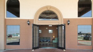 A building entrance with a brick pathway leading to a seating area and a reception desk. - Americas Best Value Inn Pharr (Pharr)