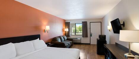 Una habitación de hotel con una cama grande, un escritorio, un sofá y un televisor.
