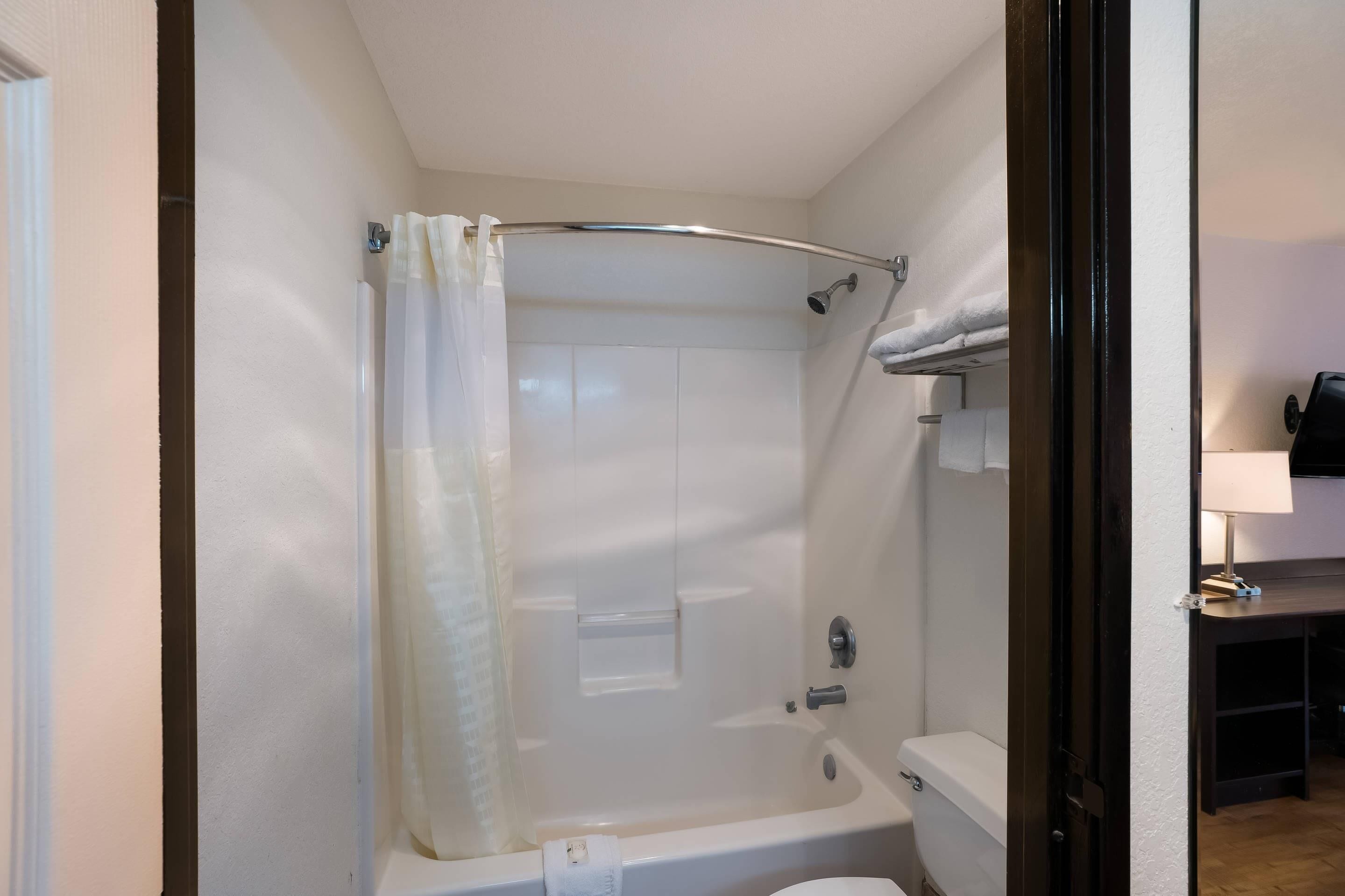 A bathroom with a shower, toilet, and a towel rack.