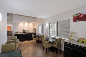 A modern kitchen with a dining area, featuring a kitchen island, built-in appliances, and a dining table with chairs.