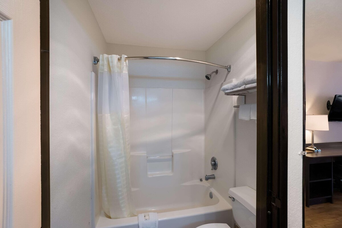 Et badeværelse med brusebad, toilet og håndklædetørrestativ.