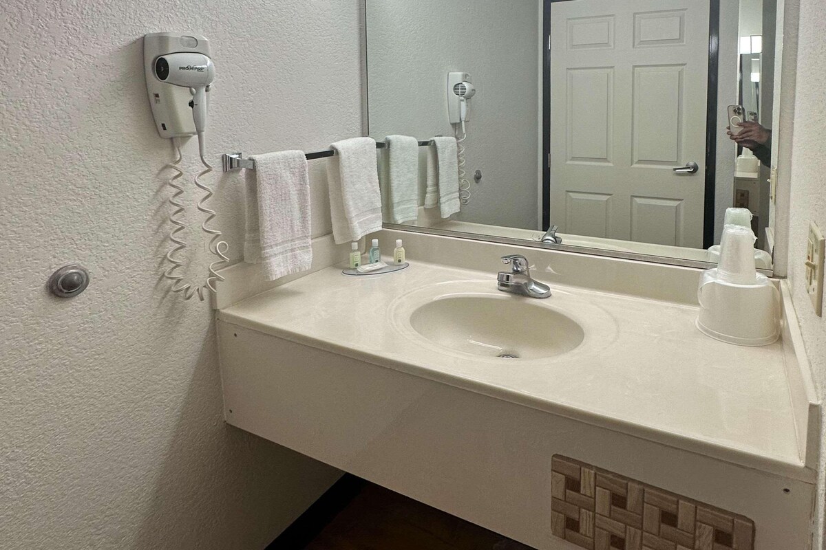 A bathroom with a sink, mirror, towel rack, and hair dryer.