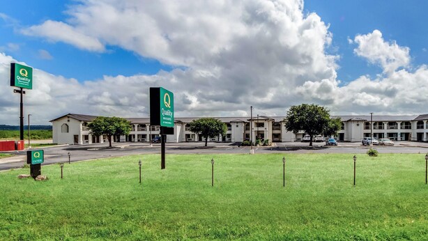 A hotel with a large parking lot, multiple buildings, and a grassy area with signs.