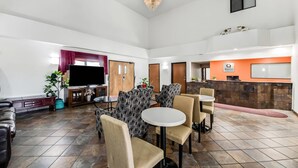 A spacious lobby with a reception desk, seating area, and a television.