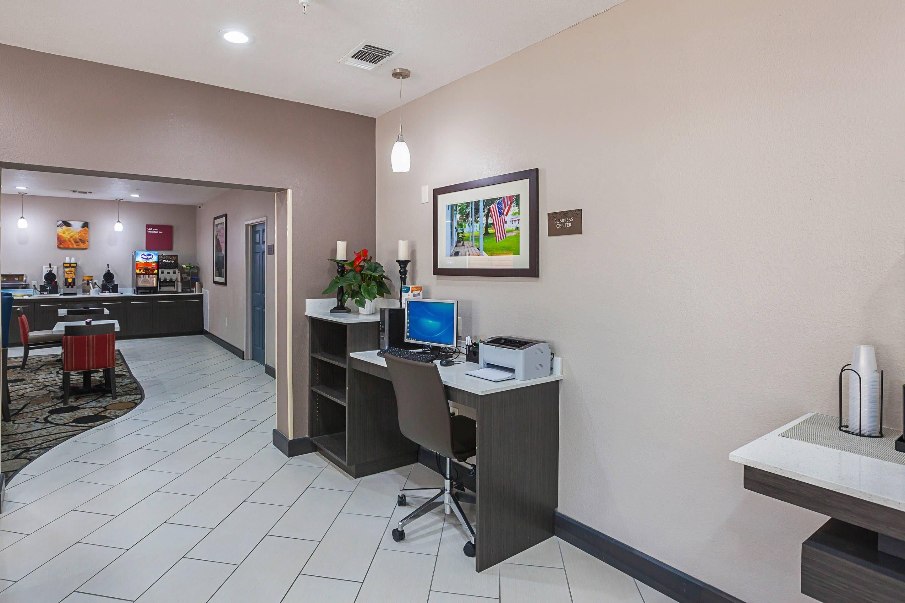 Zona de recepción de hotel con mostrador, computadora y un cuadro en la pared.