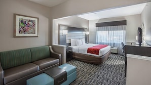 A hotel room with a bed, a sofa, a desk, and a nightstand. - Comfort Suites Lewisville - Dallas (Lewisville)