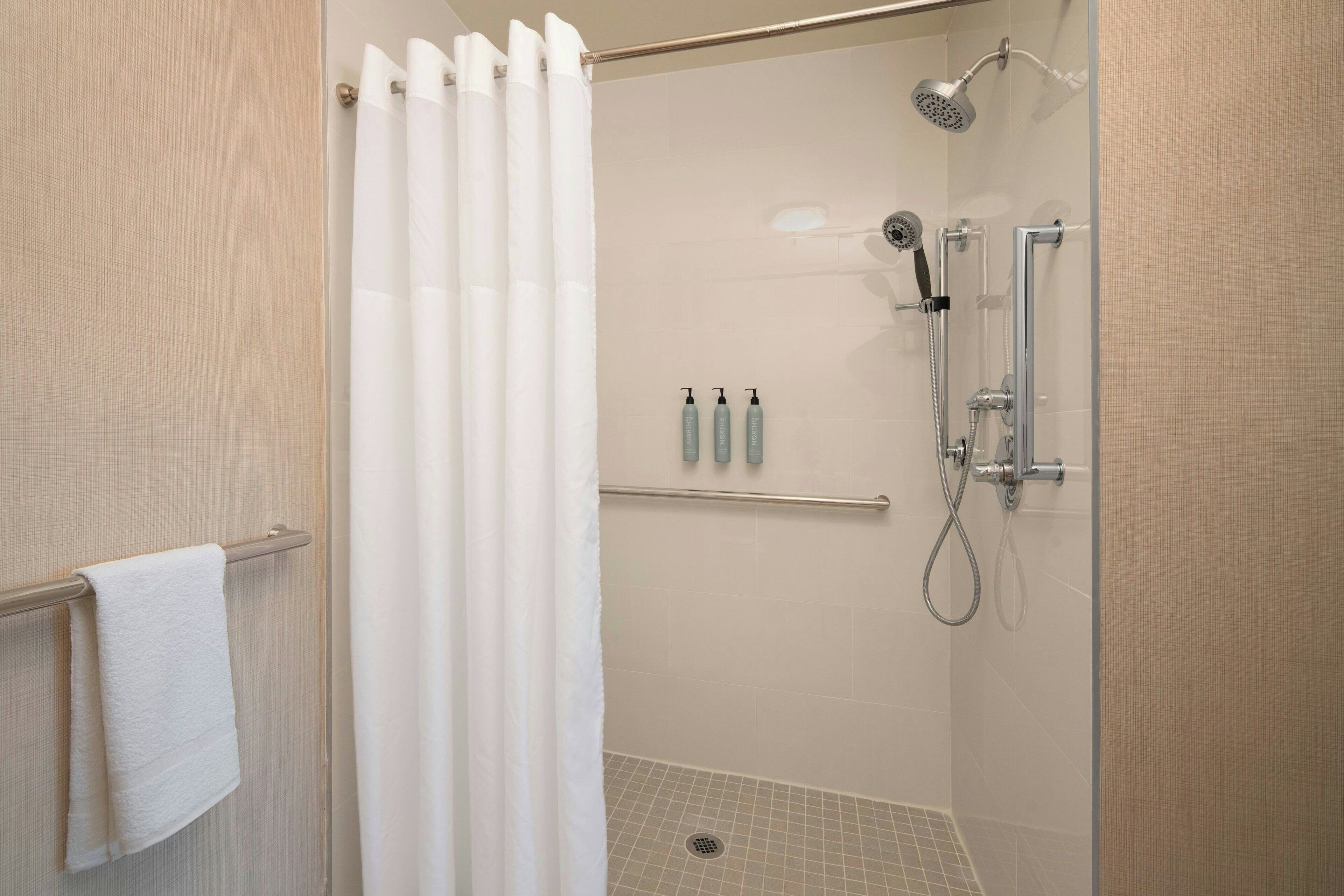 A shower with a glass door, a towel rack with a white towel, and a showerhead.