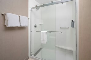 A glass-enclosed shower with a towel rack, a hand dryer, and a soap dispenser.