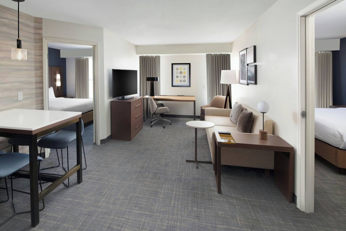 Habitación de hotel con cama, escritorio, sillón, sofá, televisor y lámpara.