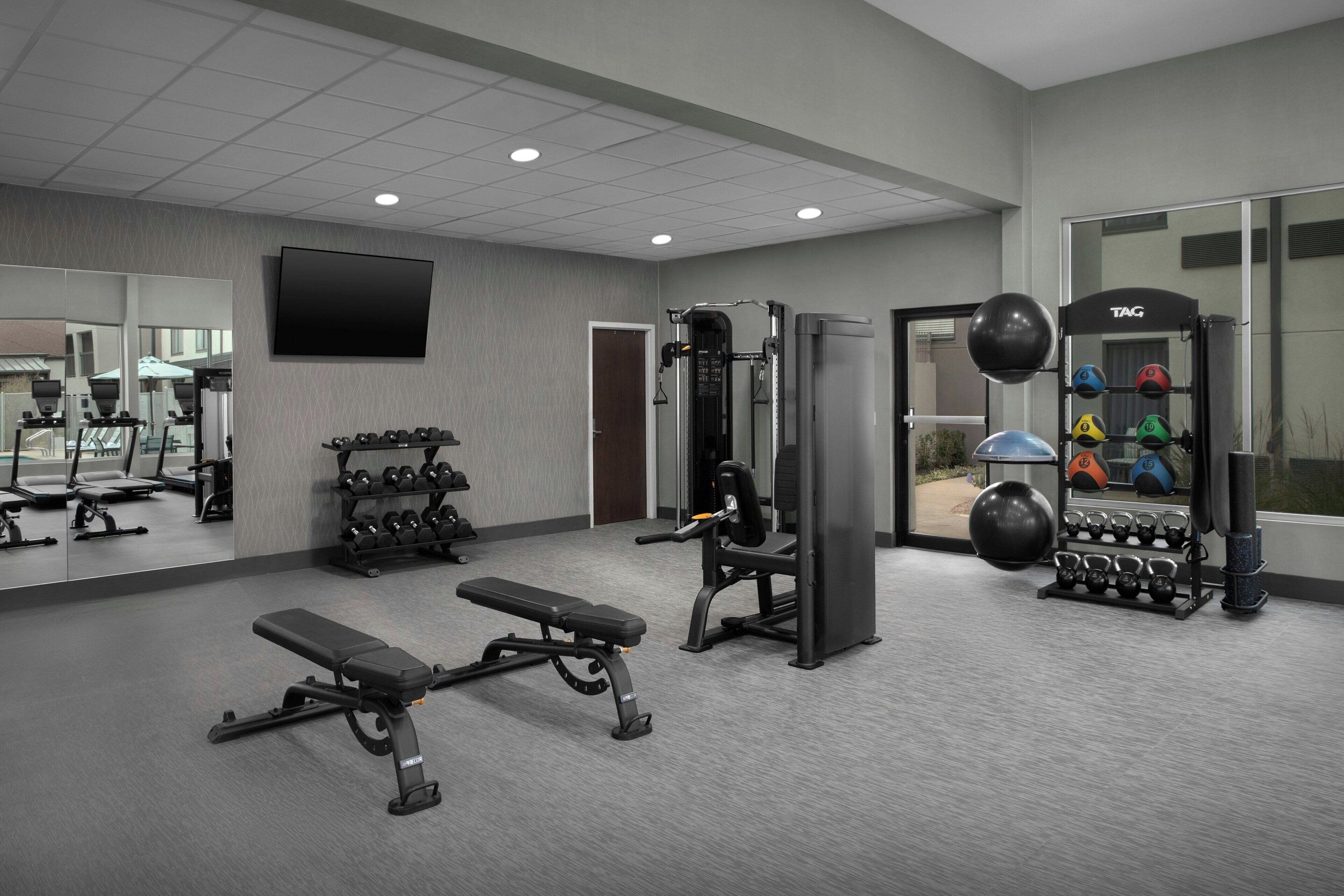 A gym with weightlifting equipment, benches, and dumbbells.
