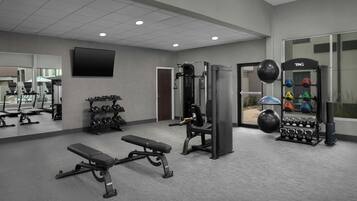A gym with weightlifting equipment, benches, and dumbbells.