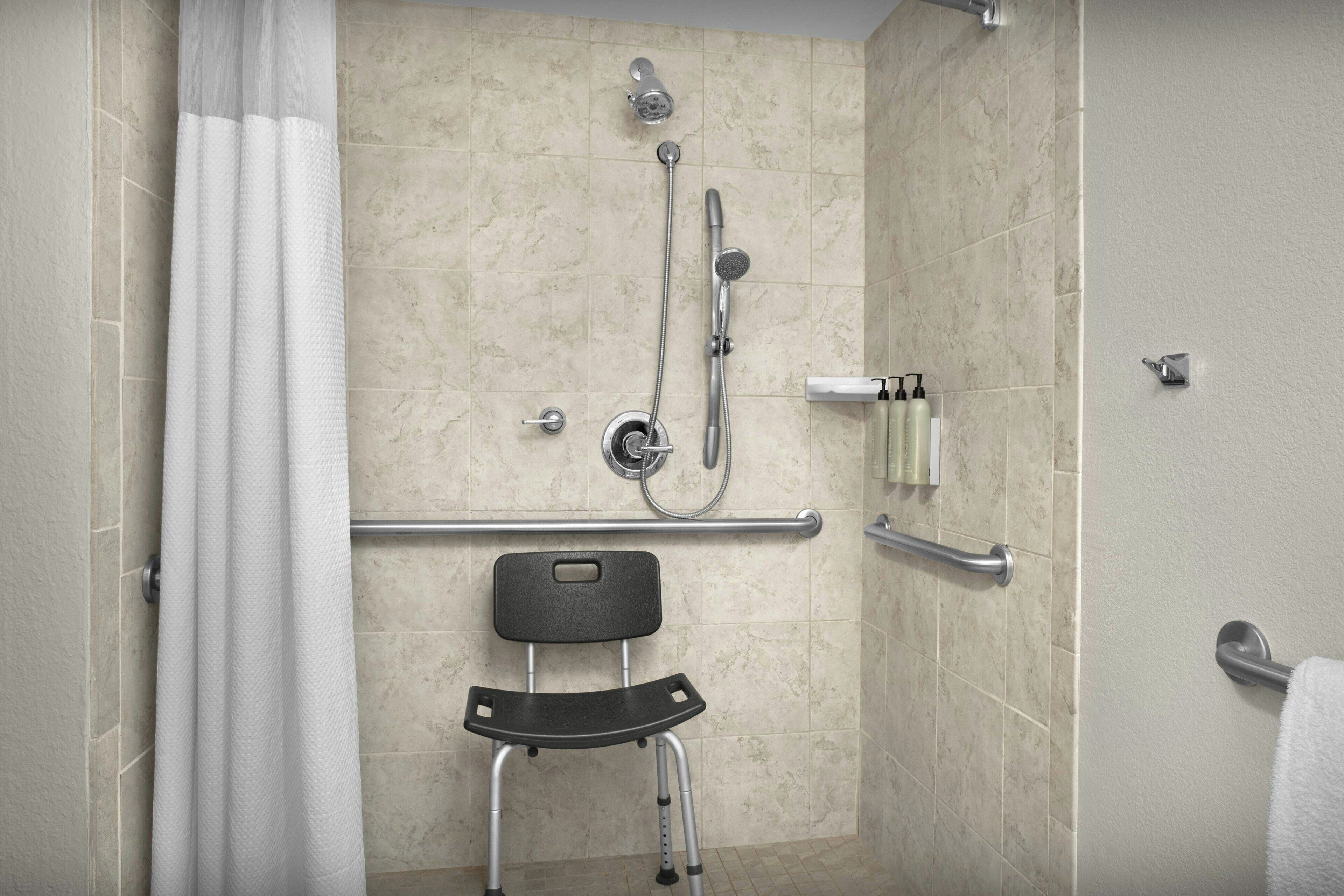 Un espace douche équipé d’une barre d’appui, d’une chaise et d’un porte-serviettes.