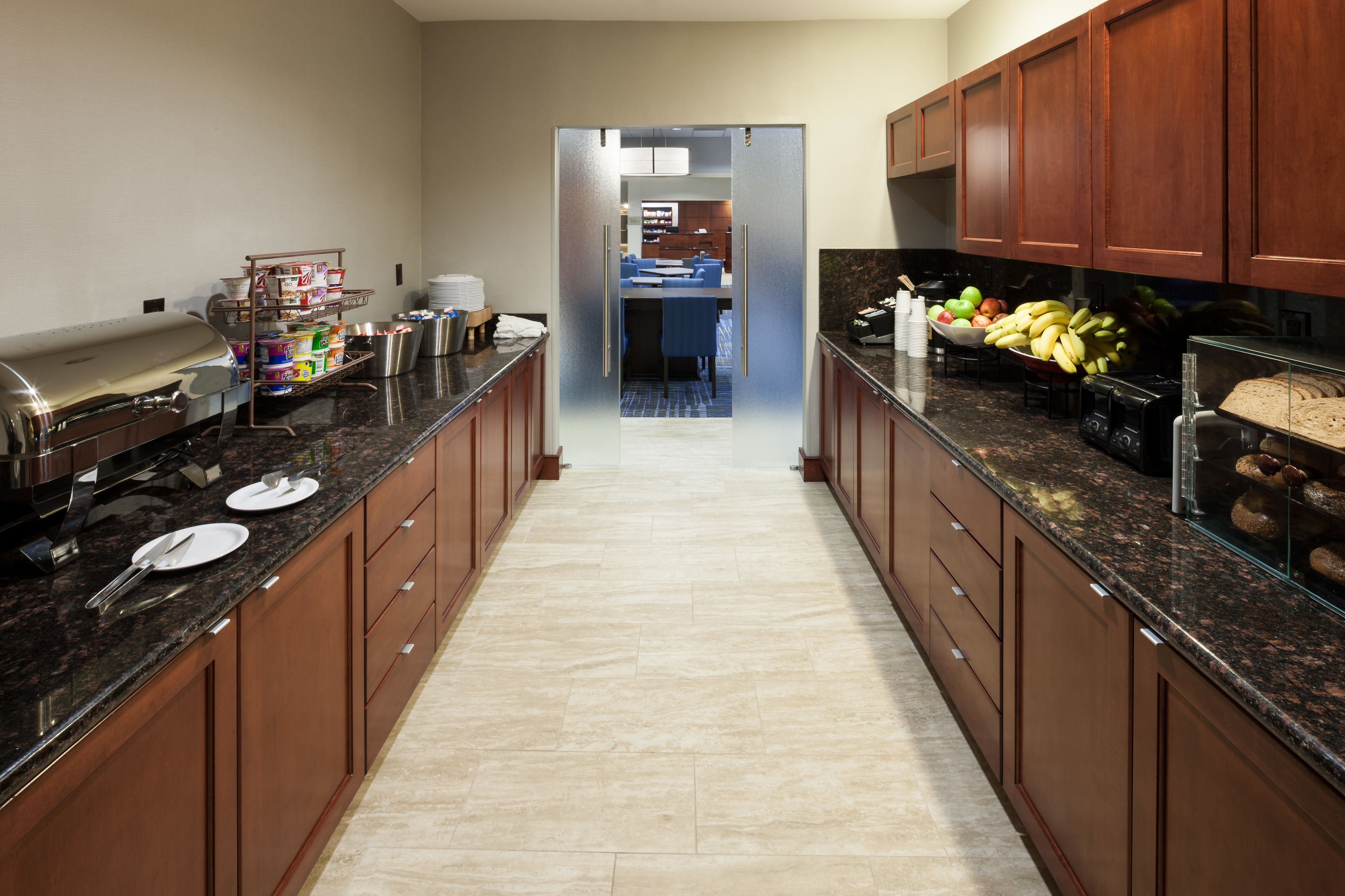 A modern kitchen with granite countertops, wooden cabinets, and a central island with a sink.
