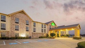 A hotel with a stone facade, a covered entrance, and a parking lot with handicapped spaces.