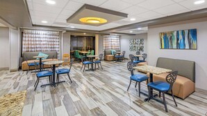 A modern lounge area with multiple seating options including sofas and tables, a patterned floor, and a ceiling with recessed lighting.