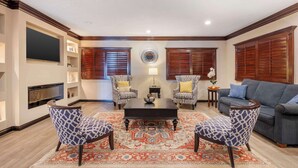 A living room with a fireplace, two patterned armchairs, a sofa, a coffee table, and a decorative rug.