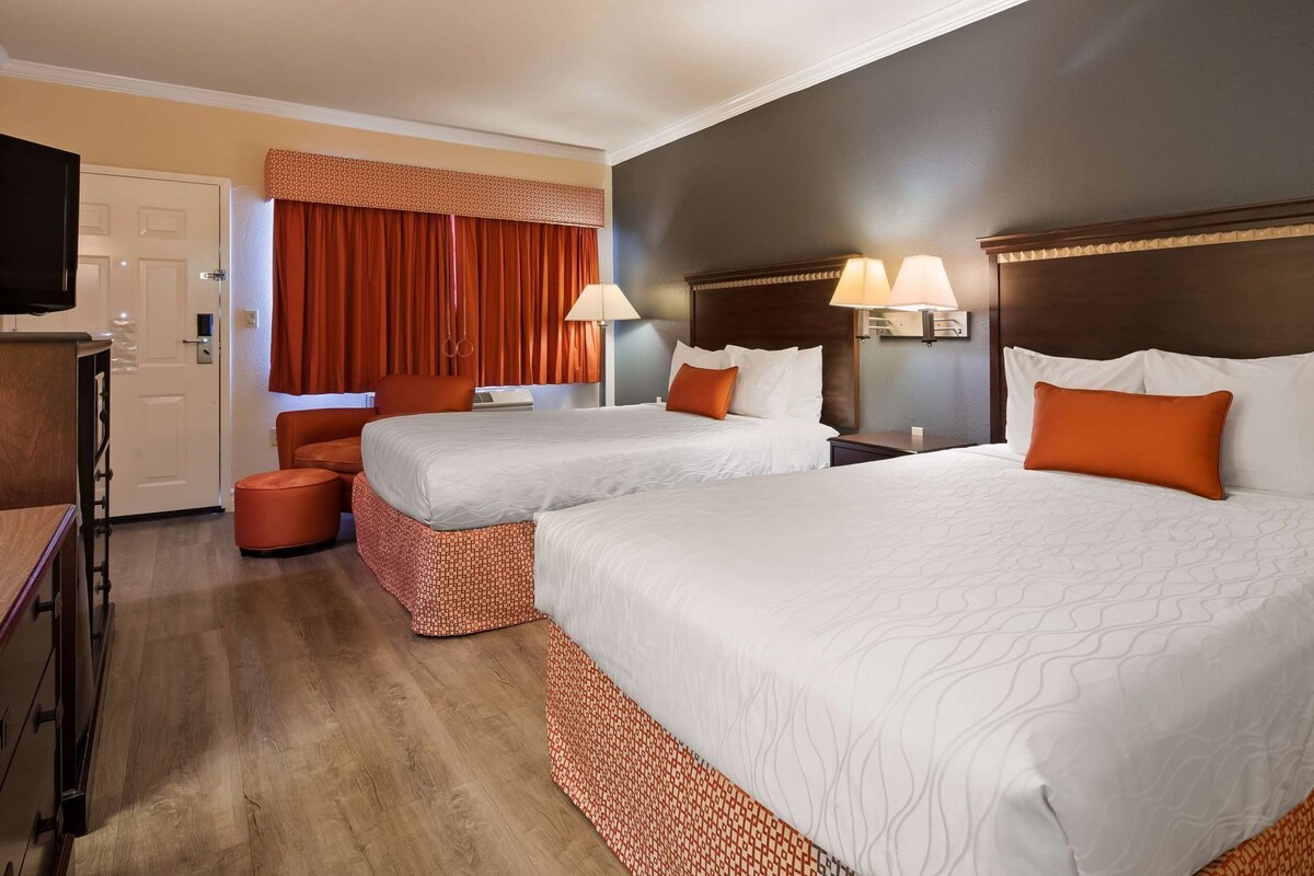 Habitación de hotel con dos camas, un televisor, un escritorio y una silla.
