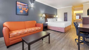 A hotel room with a bed, a sofa, a desk, and a nightstand.