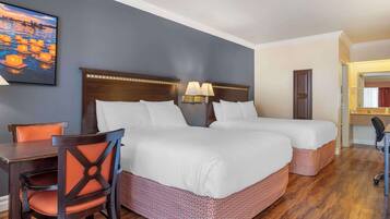 A hotel room with two beds, a desk, a chair, and a painting on the wall.