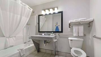 Un baño moderno con una bañera, un lavabo con espejo y un inodoro, además de un perchero con toallas.
