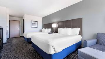 Habitación de hotel con dos camas, un escritorio, una silla y piso alfombrado.