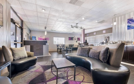 A modern hotel lobby with leather sofas, a coffee table, and a patterned rug.