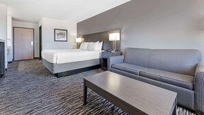 A hotel room with a bed, a sofa, a nightstand with a lamp, and a small table. - Best Western Santa Fe (Amarillo)