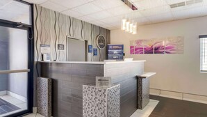 A reception area with a modern design, featuring a reception desk, a clock, and a wall-mounted artwork. - Best Western Santa Fe (Amarillo)